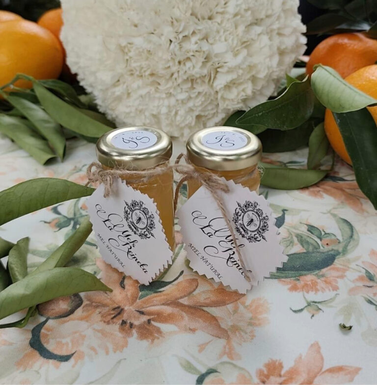 Frascos de miel artesanal natural Mels La Reineta, decorados con etiquetas personalizadas y atados con cuerda, rodeados de hojas y frutas frescas.